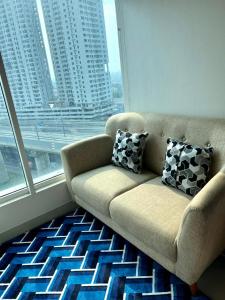 - un canapé dans une chambre avec une grande fenêtre dans l'établissement Grand Kamala Lagoon Bekasi Apartement, à Pekayon Satu