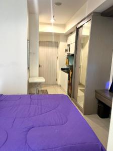 uma grande cama roxa num quarto com um armário em Grand Kamala Lagoon Bekasi Apartement em Pekayon Satu