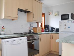 a kitchen with white appliances and wooden cabinets at Hillside - Uk32930 in Gairloch