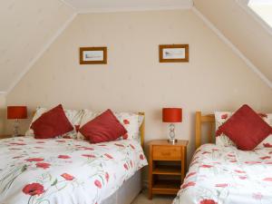 a bedroom with two beds with red pillows at Hillside - Uk32930 in Gairloch