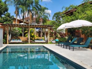 a swimming pool with two chairs and an umbrella at Confraria da Prata Flats in Pirenópolis