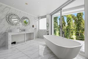 a white bathroom with a tub and a large window at The Fairways Villas - 5 bedrooms & bathroom for up to 14 guests 7kms to Patong in Kathu