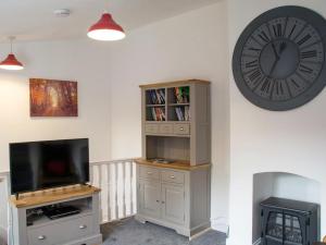 a room with a clock and a tv and a book shelf at Hawkes Lane in Canterbury