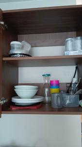 a shelf with plates and bowls and other dishes at Seaview and Cityview Mactan,Cebu in Lapu Lapu City