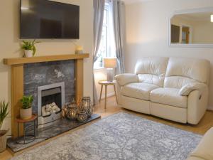 a living room with a white couch and a fireplace at Buckle House in Gatehouse of Fleet