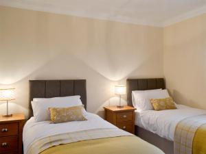duas camas num pequeno quarto com duas lâmpadas em Wheatfield House em Kilmaurs
