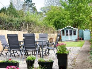 a patio with chairs and a table and a shed at Buckle House in Gatehouse of Fleet
