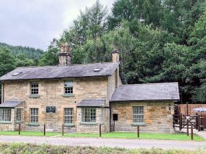 an old stone building with two chimneys on top at Stephenson Cottage - Uk38153 in Newton
