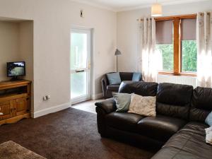 Brae Cottage في Kelton: غرفة معيشة مع أريكة جلدية وتلفزيون