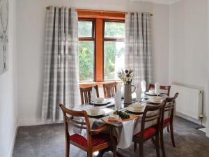 Brae Cottage في Kelton: غرفة طعام مع طاولة مع كراسي ونافذة