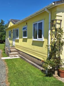 a yellow house with stairs and windows on it at Thornbury Holiday Park in Thornbury