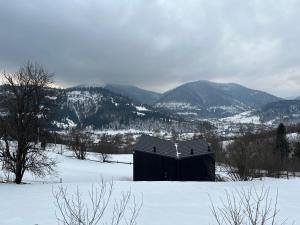 an old barn in the snow with mountains in the background at CloudBase in Tukhlya +7 photos