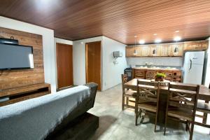 eine Küche und ein Esszimmer mit einem Tisch und einem TV in der Unterkunft Chalé do Litoral in Penha