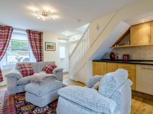 a living room with two chairs and a kitchen at Margaret House in Chirnside