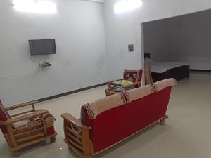 a room with a couch and a tv and a bed at Narayan nivas homestay in Ujjain