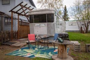 an rv with chairs and a table in a yard at Vintage Trailer - Cute Spot for Budget Travelers in Anchorage