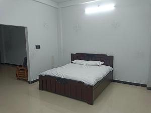 a bed in a room with a white wall at Narayan nivas homestay in Ujjain