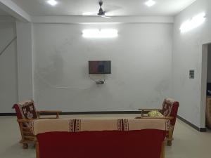a room with a table and a tv on a wall at Narayan nivas homestay in Ujjain +2 photos