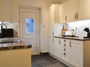 una cocina con armarios blancos y fregadero en Lealholme, en Bassenthwaite