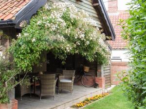 a patio with a table and chairs and a tree at The Old Bakery in Pulham Saint Mary Magdalene