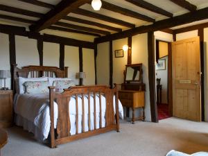 ein Schlafzimmer mit einem Holzbett und einer Kommode in einem Zimmer in der Unterkunft The Old Bakery in Pulham Saint Mary Magdalene