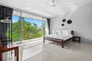 a white bedroom with a bed and a large window at The Fairways Villas - 5 bedrooms & bathroom for up to 14 guests 7kms to Patong in Kathu
