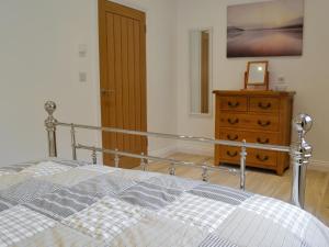 a bedroom with a bed and a wooden dresser at The Nook At Balcary in Auchencairn