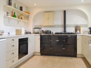 a kitchen with white cabinets and black appliances at The Sun in Ireby