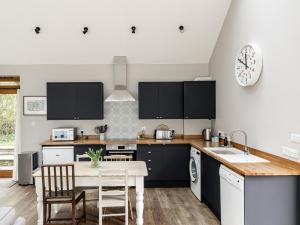 a kitchen with black cabinets and a table at The Barn At Daubeneys in Colerne