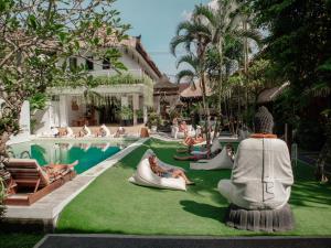 un grupo de personas sentadas en la hierba junto a una piscina en Puri Garden Hotel & Hostel, en Ubud