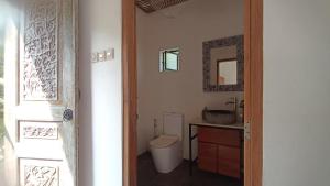 La salle de bains est pourvue de toilettes, d'un lavabo et d'un miroir. dans l'établissement Sunmoonstarvillas Yogyakarta, à Jarakan