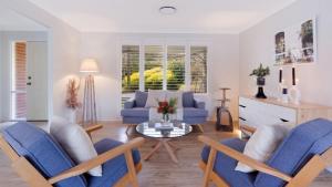 a living room with blue chairs and a table at Soho House in Bowral