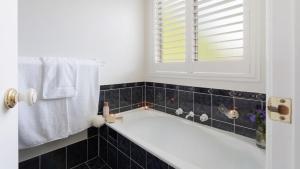 a bath tub in a bathroom with a window and towels at Soho House in Bowral