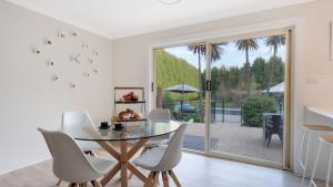 a dining room with a glass table and white chairs at Soho House in Bowral +40 photos