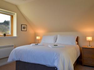 a bedroom with a large white bed with two lamps at Rowan House in Fiskavaig