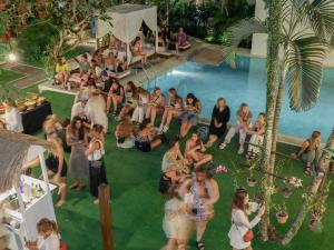 um grupo de pessoas sentadas ao redor de uma piscina em Puri Garden Hotel & Hostel em Ubud