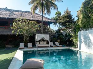a pool at a resort with chairs and a fireplace at Puri Garden Hotel & Hostel in Ubud