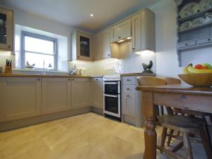 a kitchen with white cabinets and a table with a bowl of fruit at Robins Nest in Trevilley