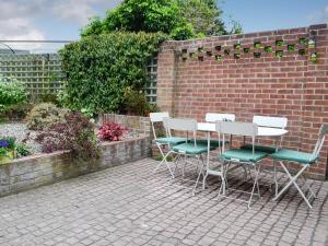 a patio with chairs and a table and a brick wall at Turnstone House in Gorleston-on-Sea
