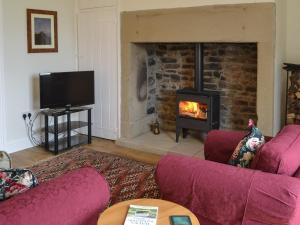 a living room with two purple couches and a fireplace at Croft Cottage in Sharperton