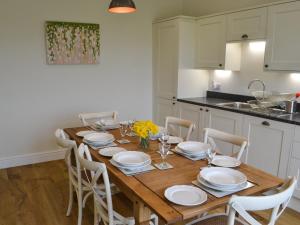 una cocina con una mesa de madera con platos y sillas blancos en Croft Cottage en Sharperton