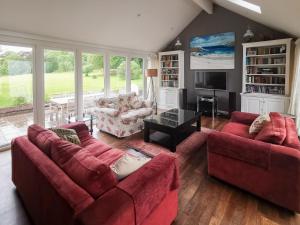 a living room with two red couches and a television at Cliff Cottage in Port Appin