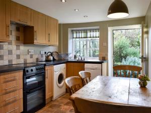 a kitchen with a table and a stove and a dishwasher at Barters Cottage in Chideock