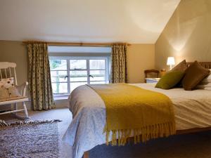 a bedroom with a bed with a yellow blanket and a window at Barters Cottage in Chideock