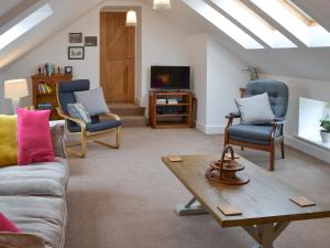 a living room with a couch and chairs and a table at Stable Cottage in Chatton
