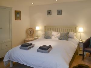 a bedroom with a large white bed with towels on it at Stable Cottage in Chatton
