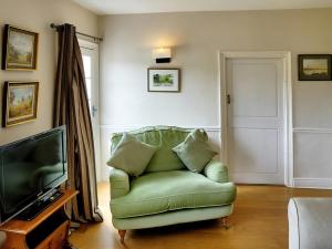 a living room with a green couch and a television at St Andrews in Tilmanstone
