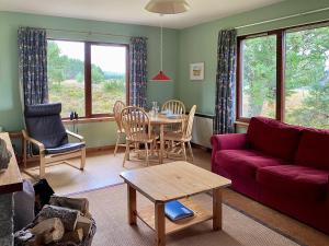 a living room with a red couch and a table at Kintulloch in Insh