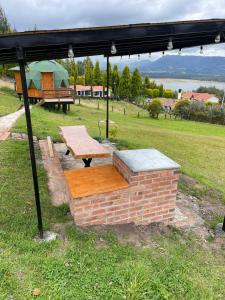 a picnic shelter with a wooden table and a bench at Glamping BRILLO DE LUNA in Guatavita