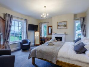 a bedroom with a bed and a chair and windows at Old Upper Gwestydd in Highgate